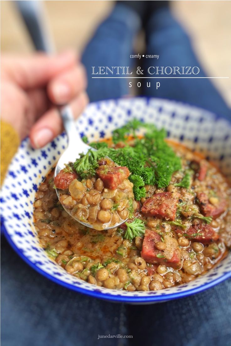 a person holding a spoon full of lentula and chorizzo soup