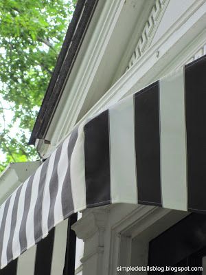 black and white striped awning on the side of a building with trees in the background