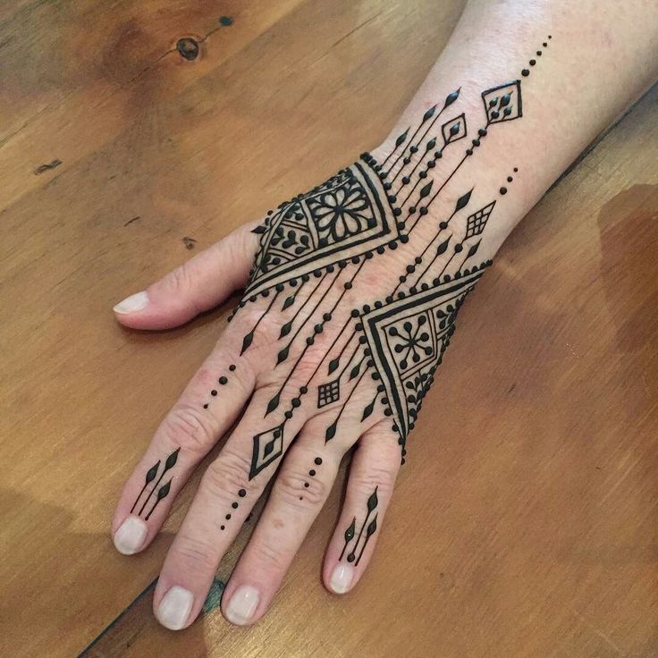 a woman's hand with black henna tattoos on her left arm and wrist