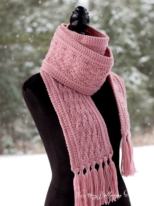 a pink knitted scarf on top of a mannequin in front of snow covered trees