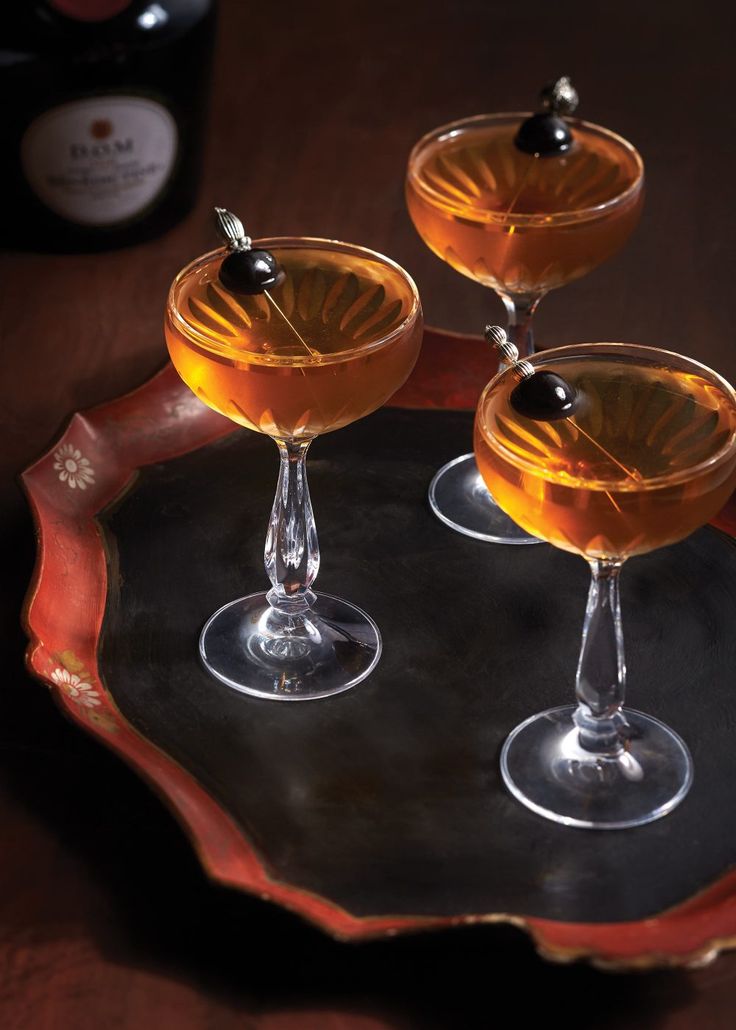 three wine glasses filled with liquid on top of a tray