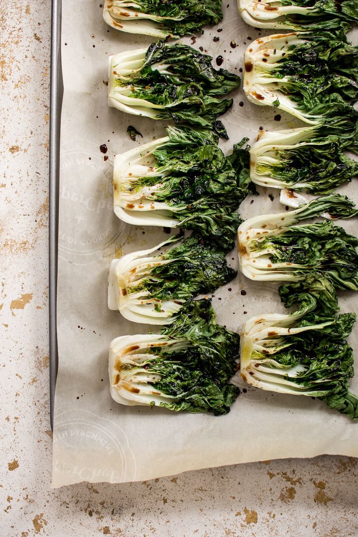 several pieces of artichoke are arranged on a sheet of parchment paper, ready to be cooked