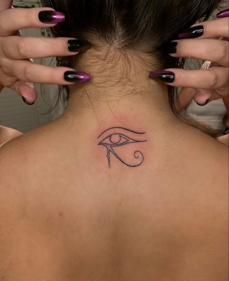 a woman's back neck with an eye tattoo on it