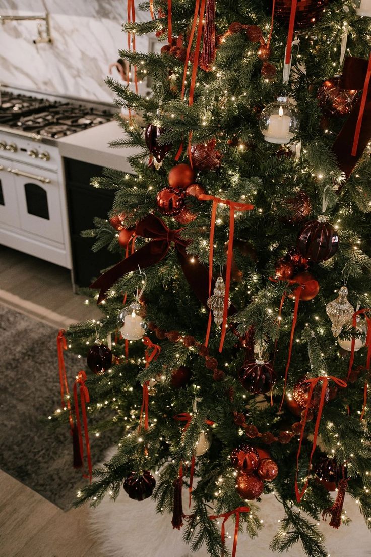 a decorated christmas tree in a kitchen with red and white ornaments on it's branches