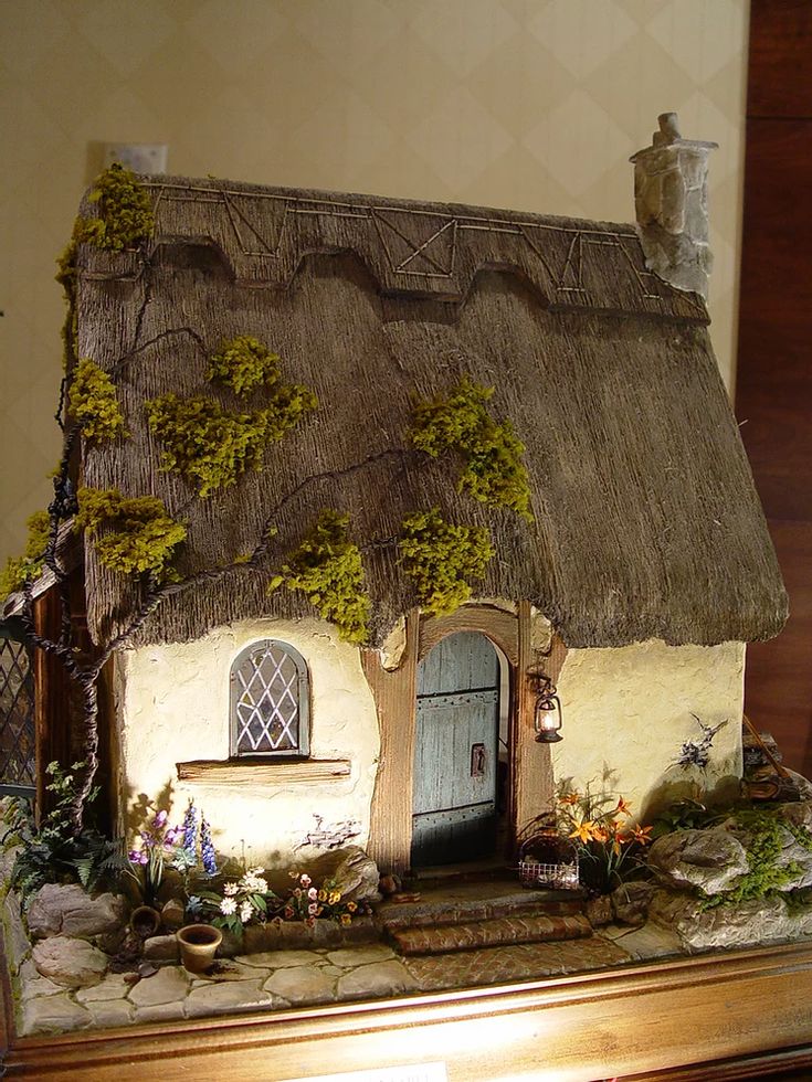 a miniature house with a thatched roof and door