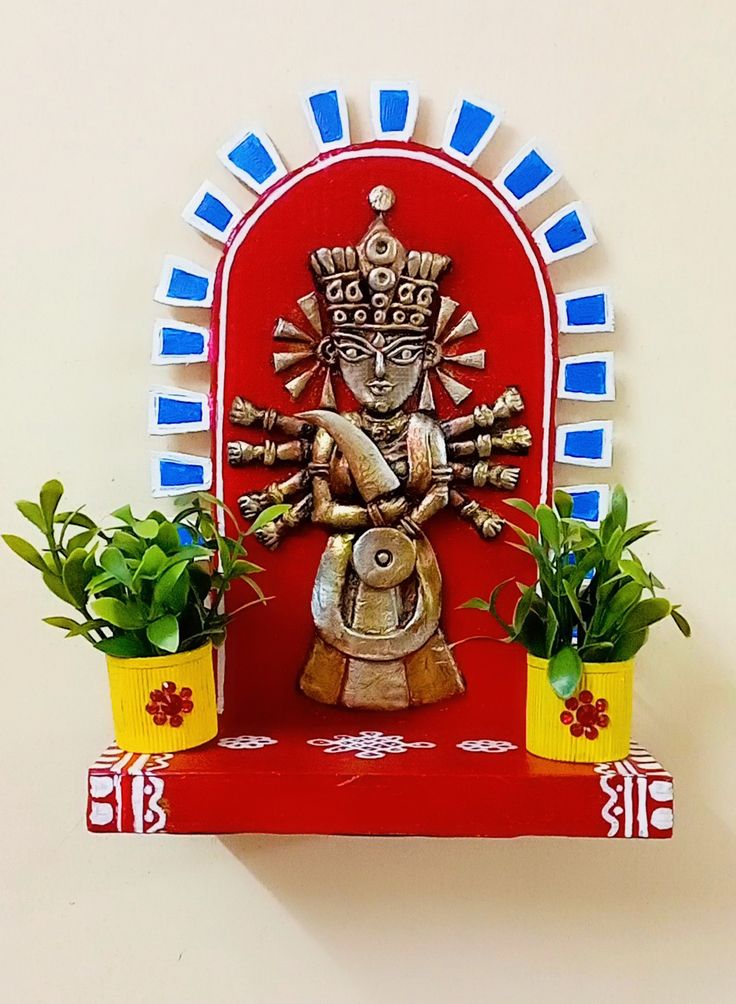 a decorative wall hanging with potted plants and a statue on the top of it