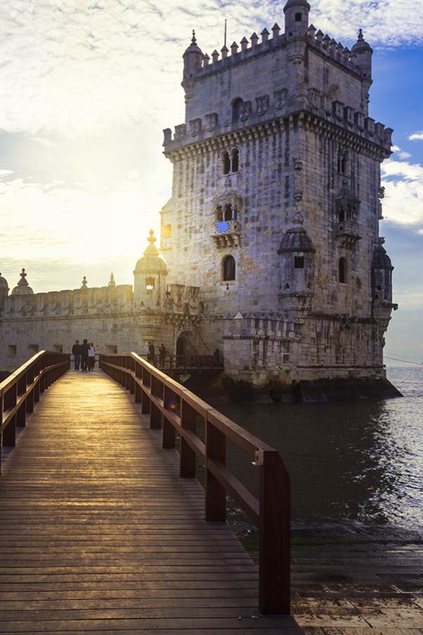 a wooden walkway leading to a large castle like structure on the water's edge