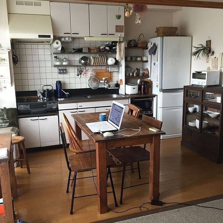 a kitchen filled with lots of appliances and furniture next to a dining room table in front of a stove top oven