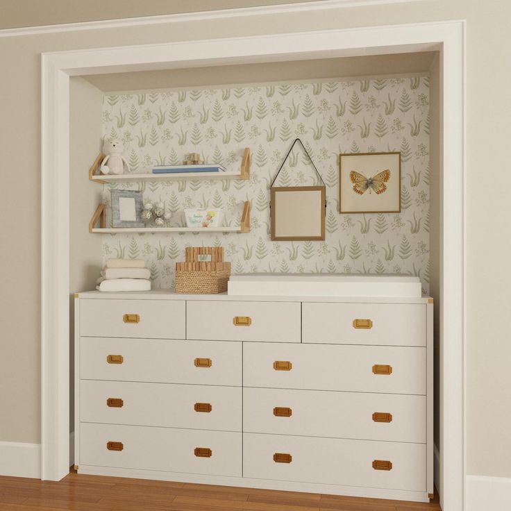 a white dresser sitting in a room next to a wall with pictures on top of it