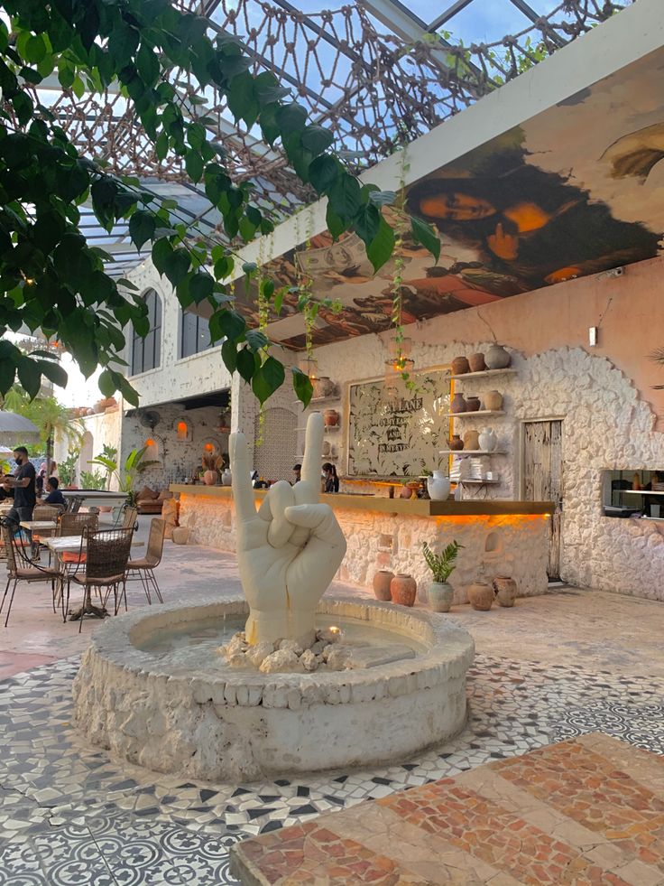 a fountain in the middle of a patio with tables and chairs