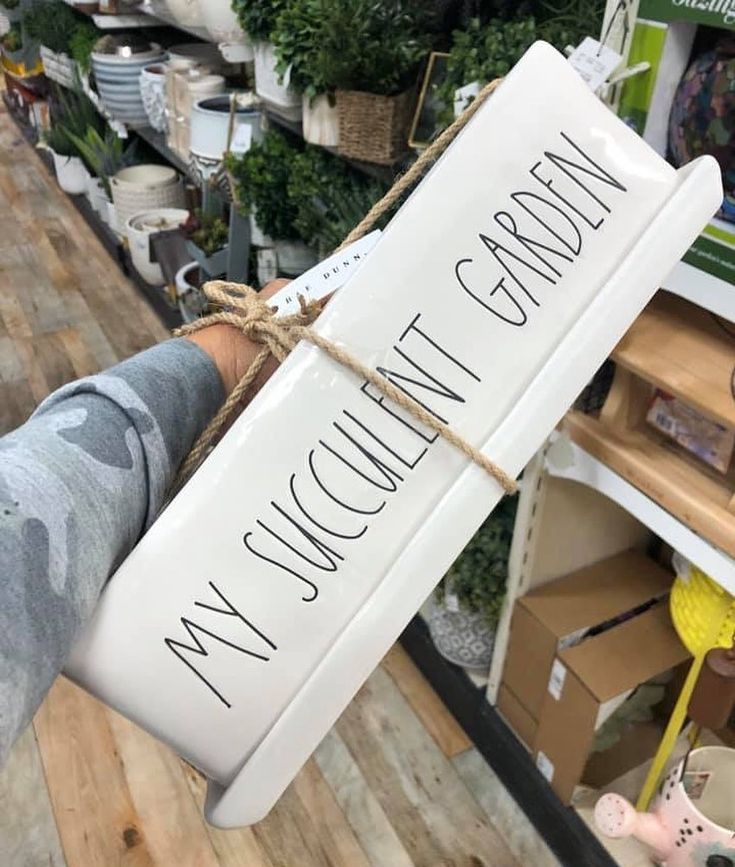 a person holding up a sign that says my garden