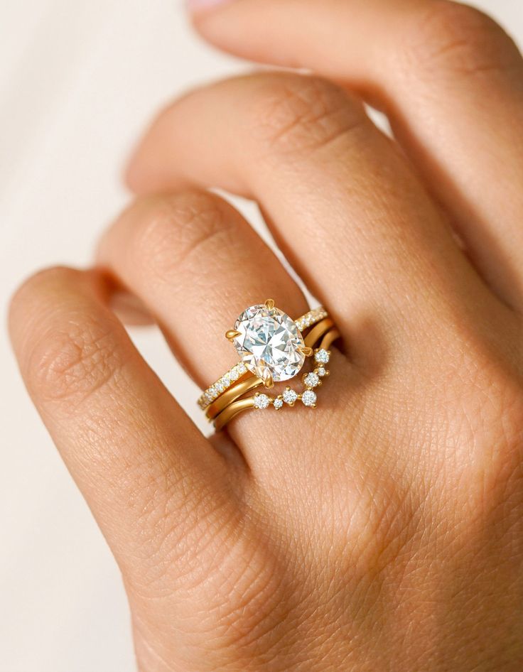 a woman's hand with a gold ring and diamond engagement ring on her finger