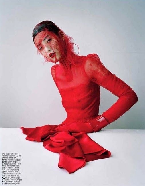 a woman in red is sitting on the floor with her hands on her hips and looking at the camera