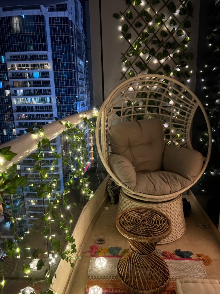 a chair and ottoman on a balcony with christmas lights in the city behind it at night