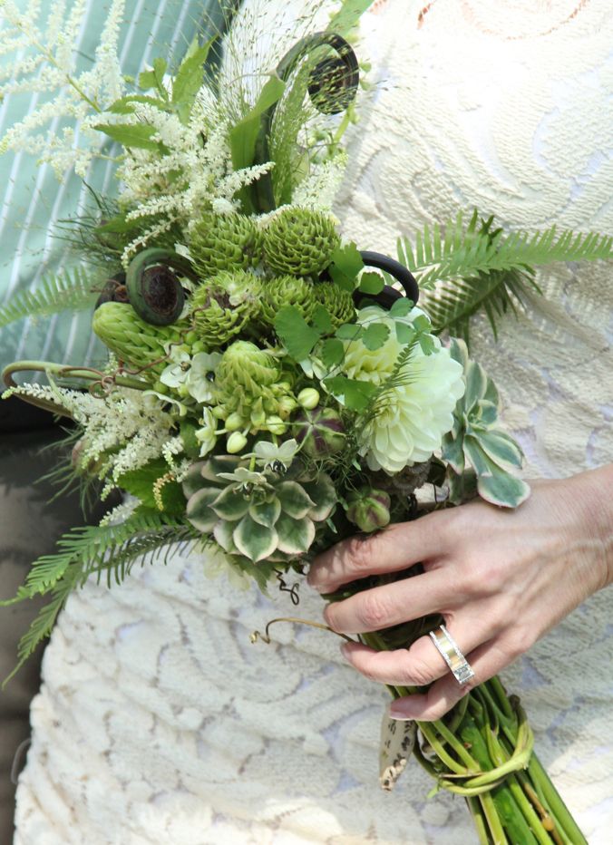 a bride holding a bouquet of flowers and greenery on her wedding day at the same time