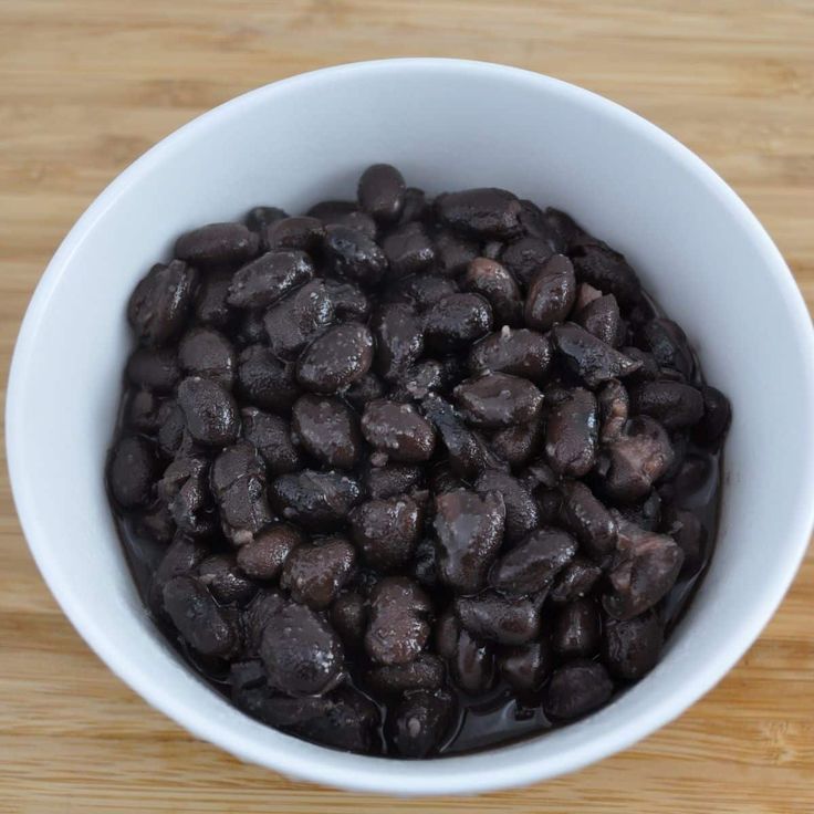 a white bowl filled with black beans on top of a wooden table