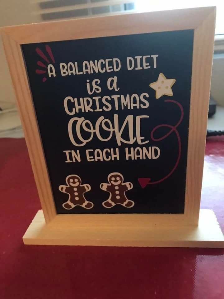 a chalkboard sign that says a balanced diet is a christmas cookie in each hand