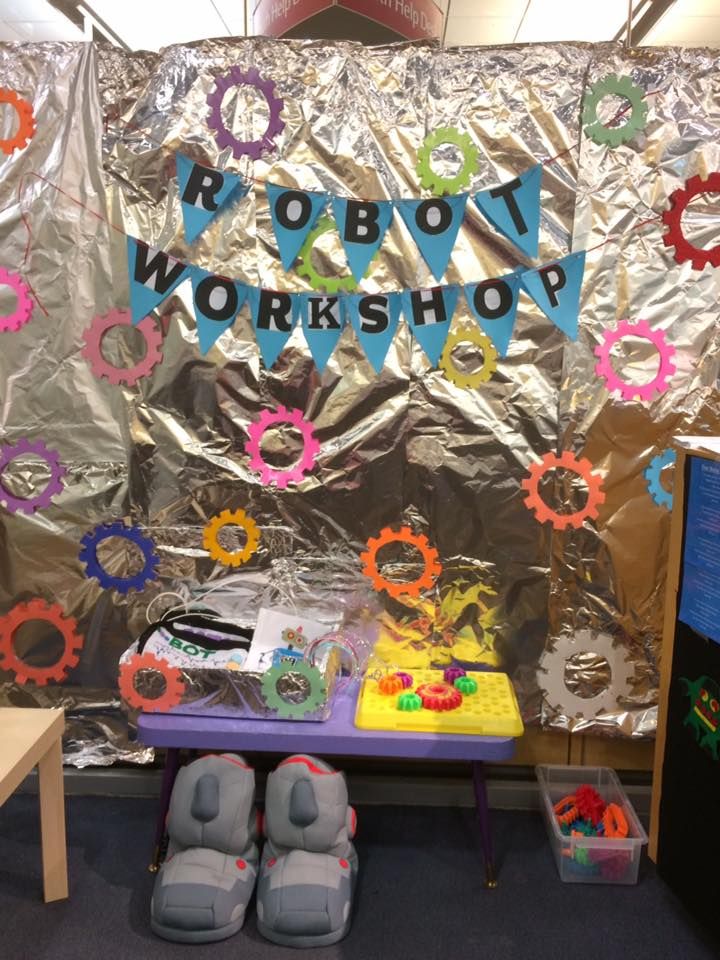 a table topped with lots of toys next to a silver sheeted wall covered in words