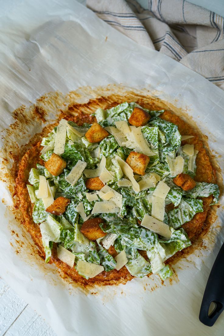 a pizza topped with lettuce and cheese on top of a white paper towel