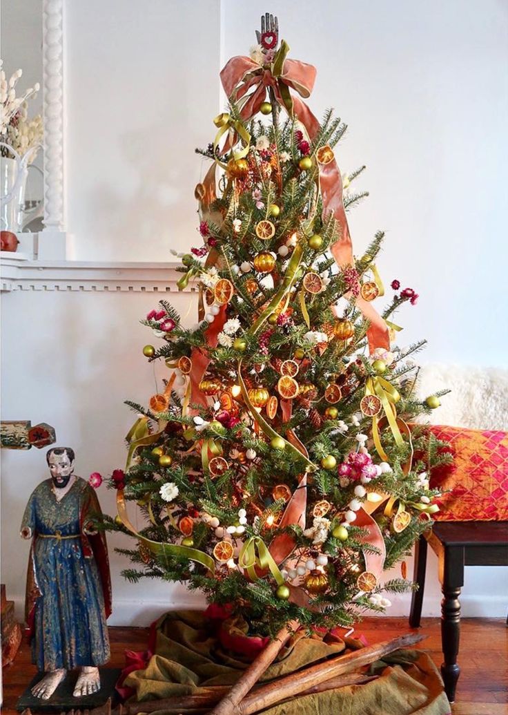 a decorated christmas tree in a living room next to a doll and other items on the floor