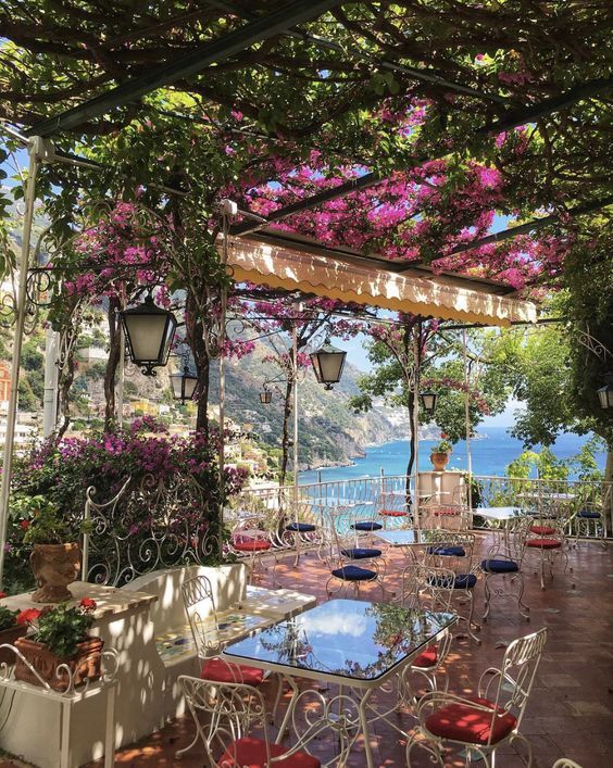 an outdoor dining area with tables and chairs under a pergolated canopy over the water