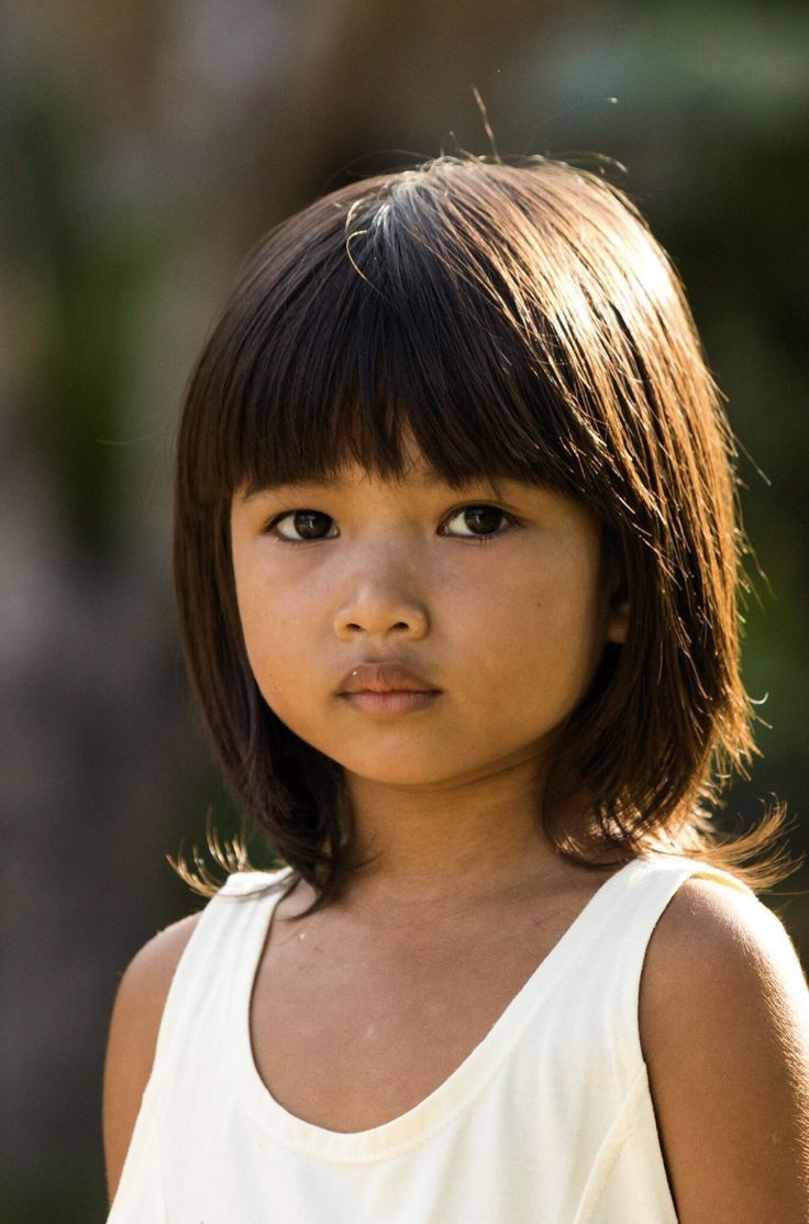 a close up of a young child wearing a white shirt and short hair with bangs