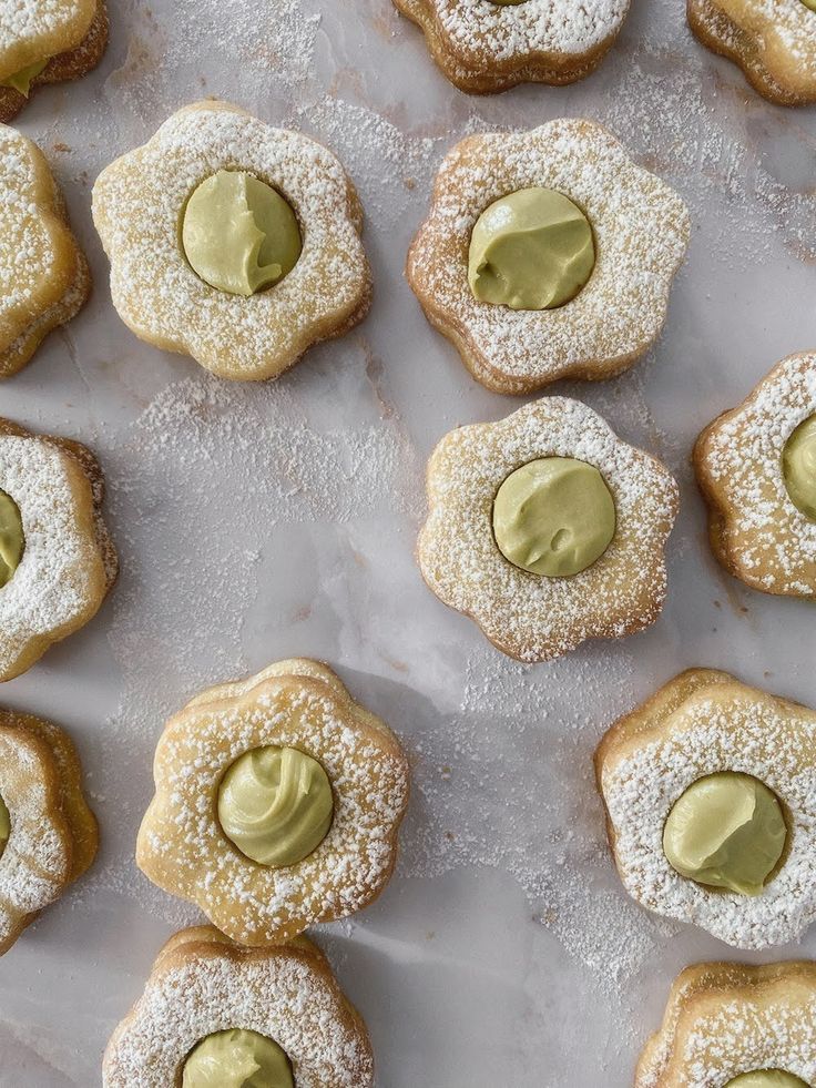 several cookies with green icing and powdered sugar on top are arranged in rows