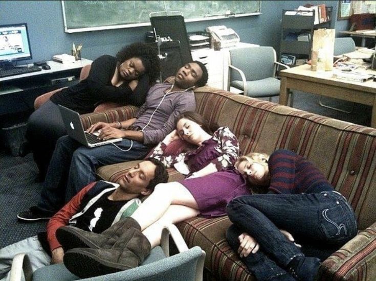 group of people lounging on couches in front of computer monitors and laptops