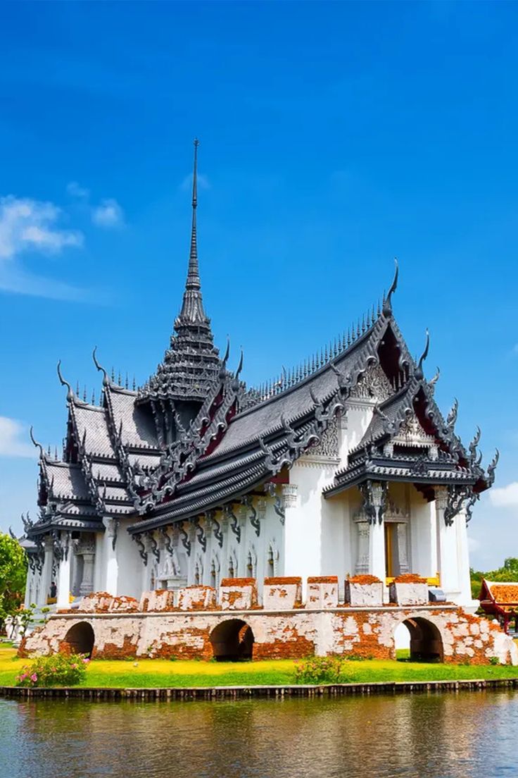 an ornate building sitting on the side of a lake in front of a blue sky