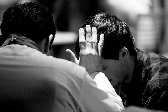 two men sitting at a table with their hands on their faces and one holding his head