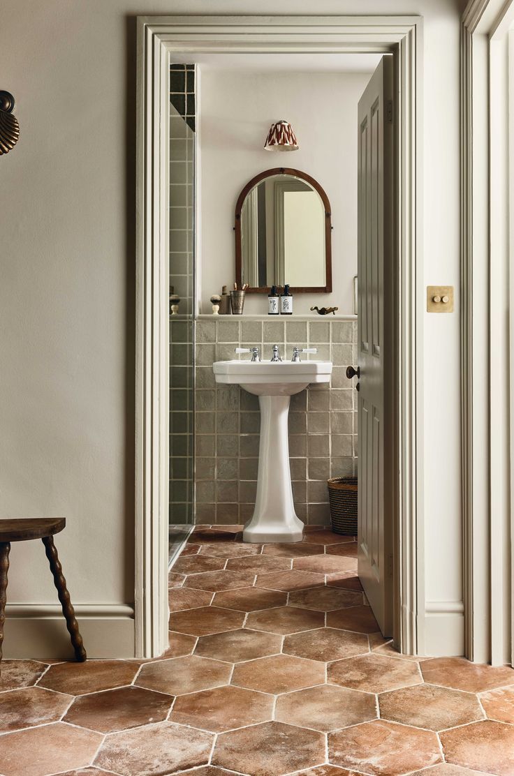 an open door leading to a bathroom with a pedestal sink and tiled floors in it