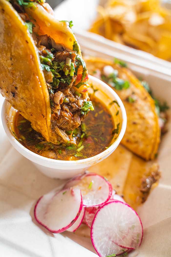 a tortilla filled with meat and vegetables next to sliced radishes