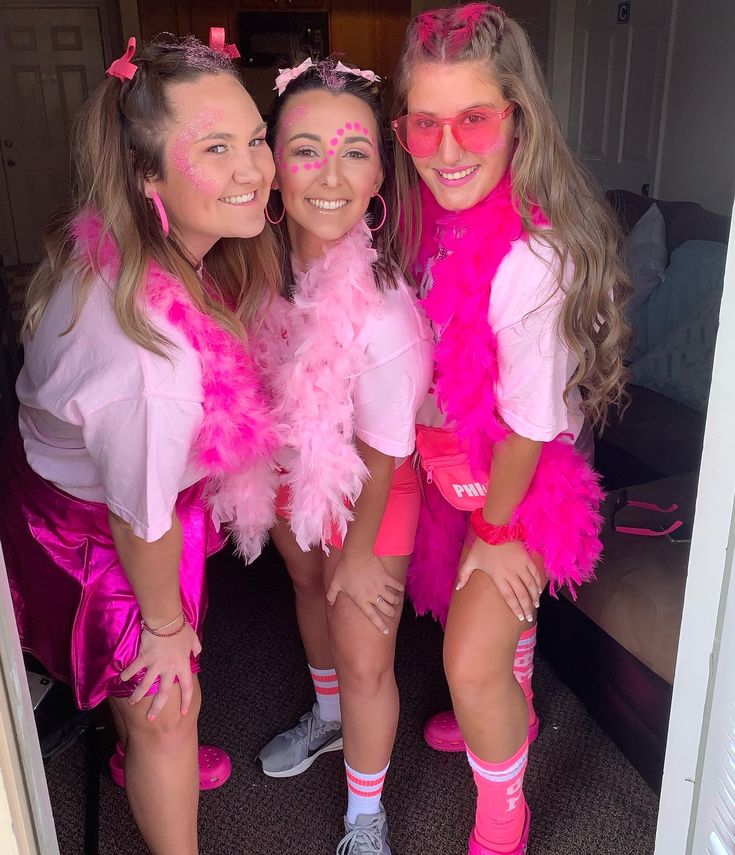 three girls dressed up in pink posing for the camera with their arms around each other