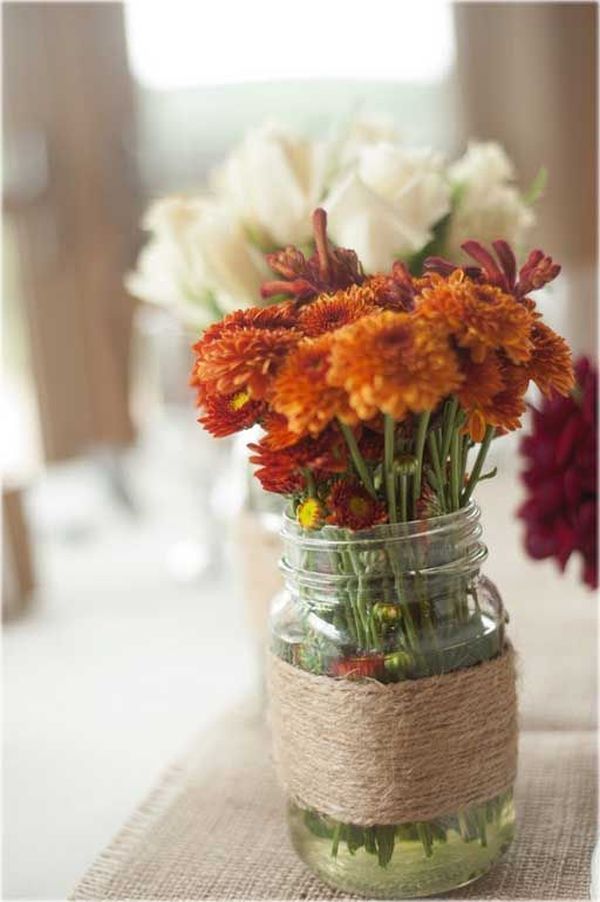 some flowers are in a mason jar on a burlocked tablecloth with twine