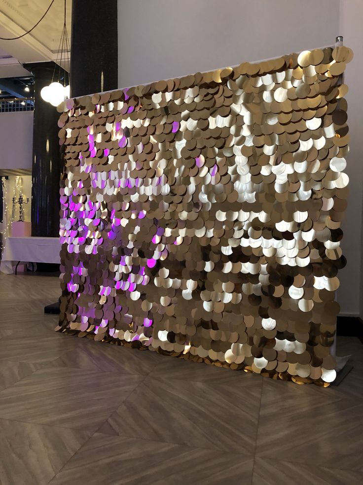 a large mirror sculpture in the middle of a room with wood flooring and purple lights