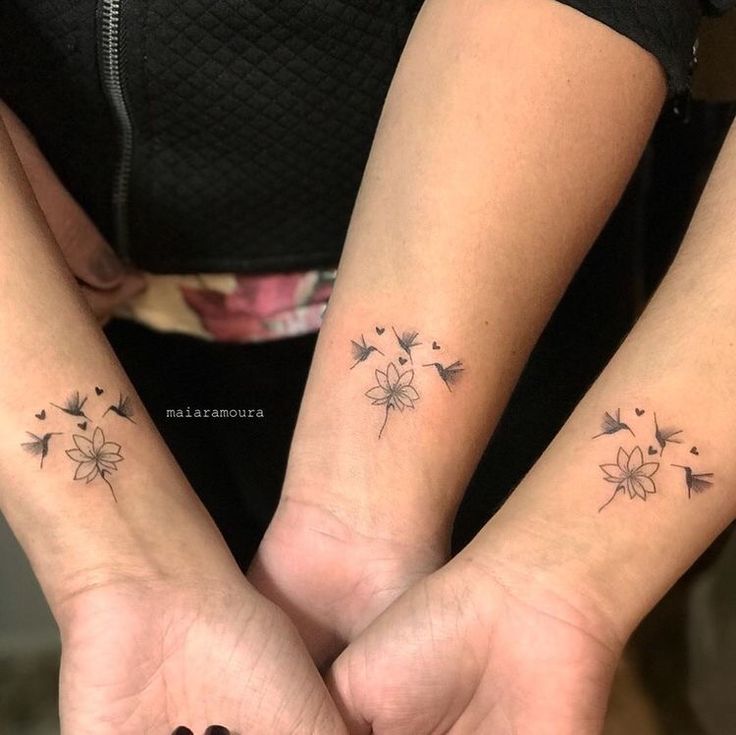 two women with matching tattoos on their arms holding each other's hands and looking at the camera