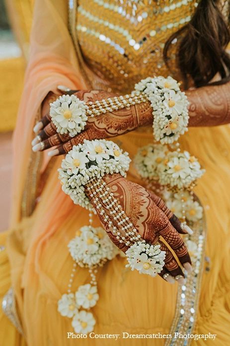 a woman in yellow dress holding flowers and two hands with hendikes on them