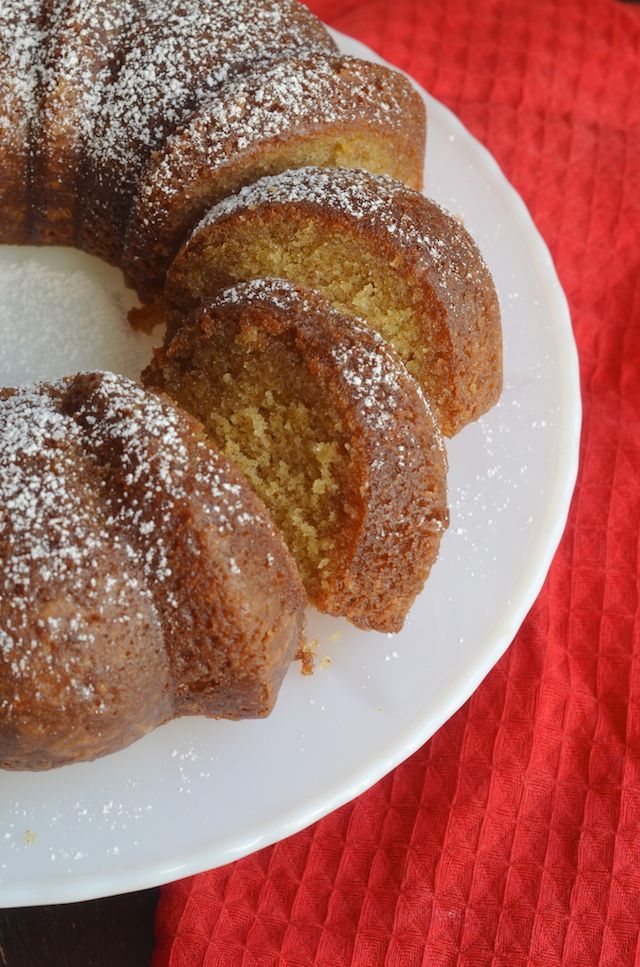 a bundt cake with powdered sugar on top sits on a white platter