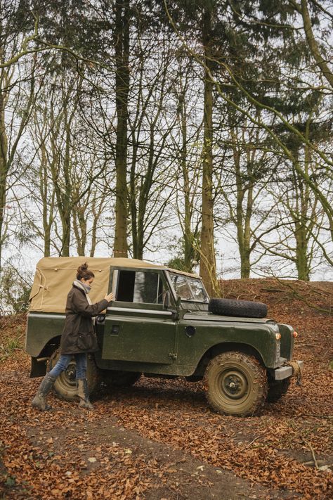 a man standing next to a green truck in the woods