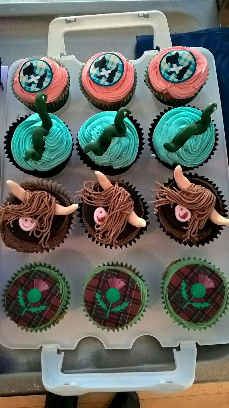 twelve cupcakes in a plastic container with green frosting and pink icing