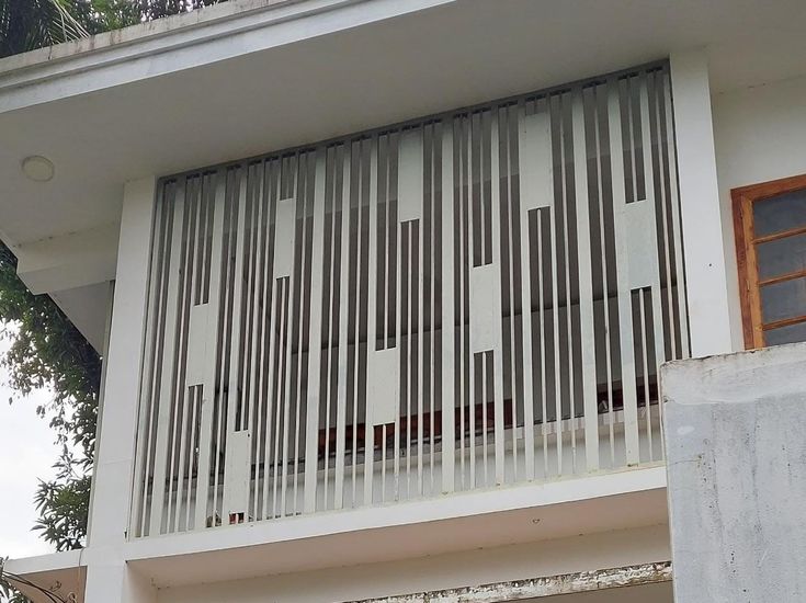 a cat sitting on top of a window sill in front of a white building