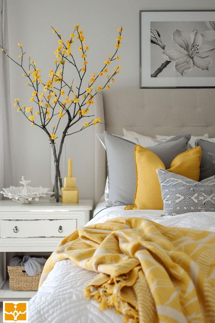 a white bed with yellow and gray pillows