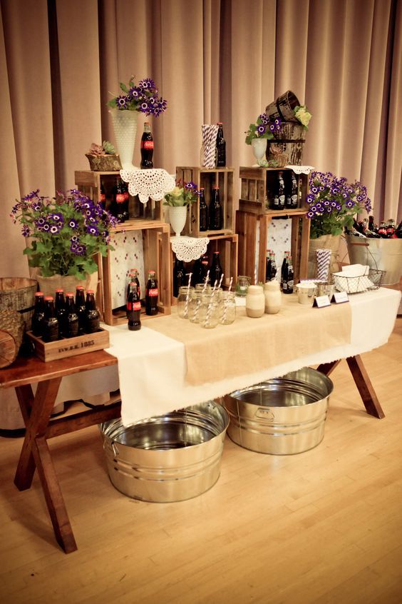 the table is set up with wine bottles and buckets on it, as well as flowers