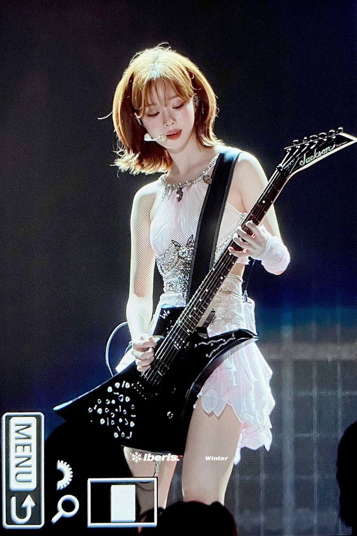 a woman in white dress playing an electric guitar