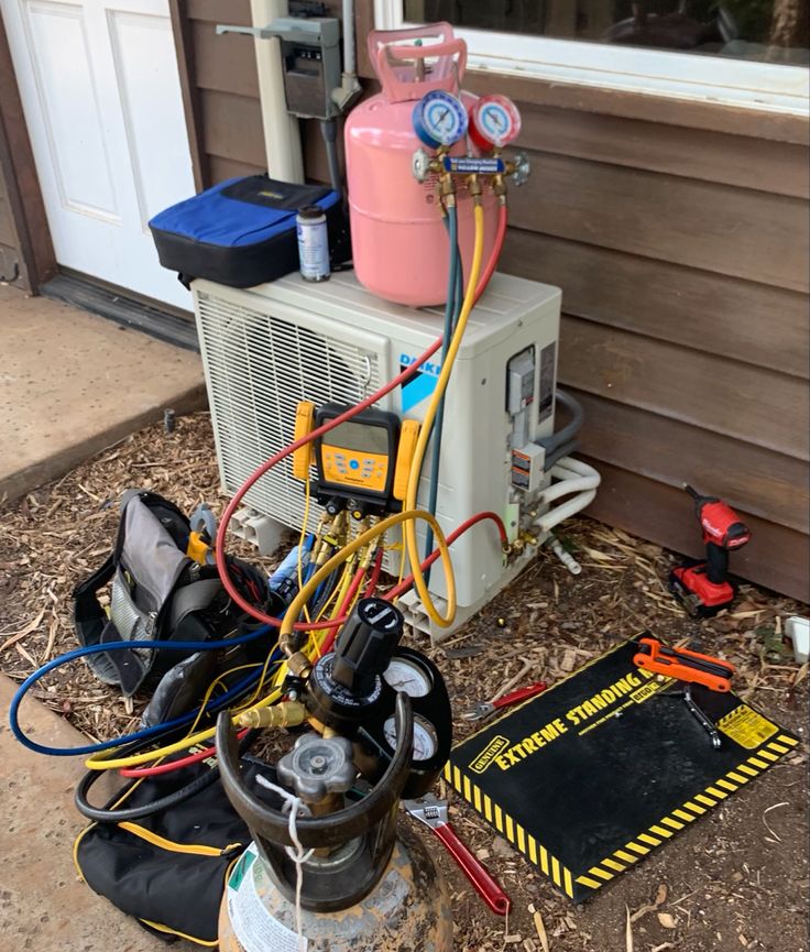 an air conditioner sitting on the side of a house next to tools and equipment