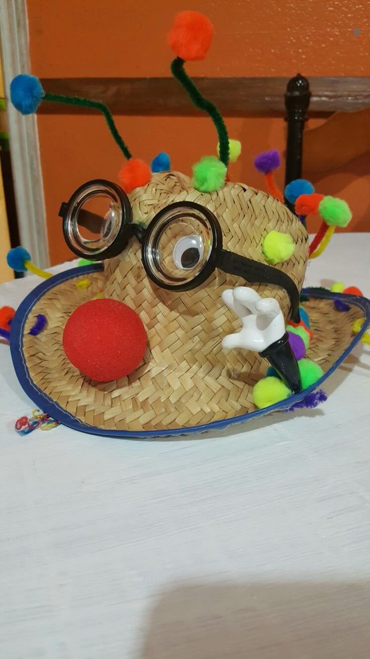 a straw hat with glasses on top of it and a clown nose made out of pom poms