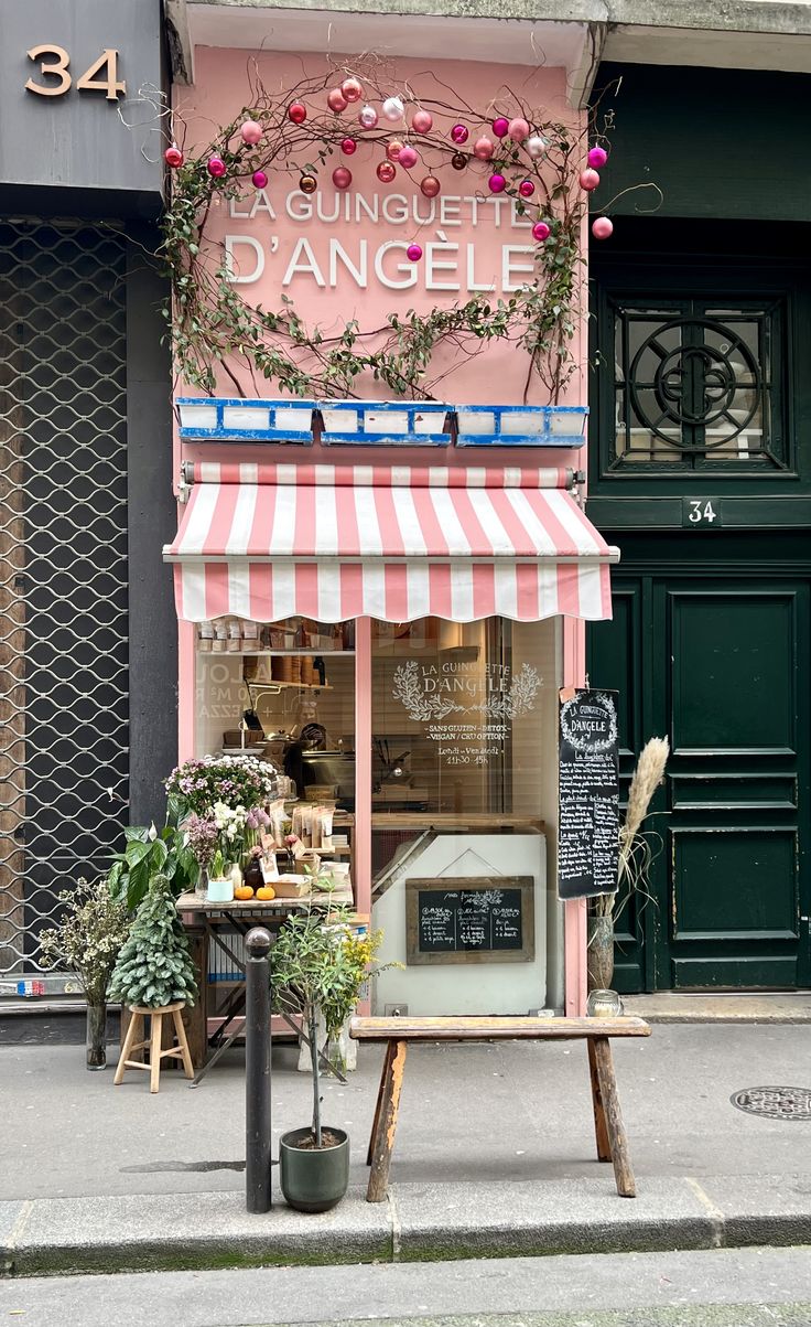 a pink and white striped awning on the side of a building with flowers growing out of it