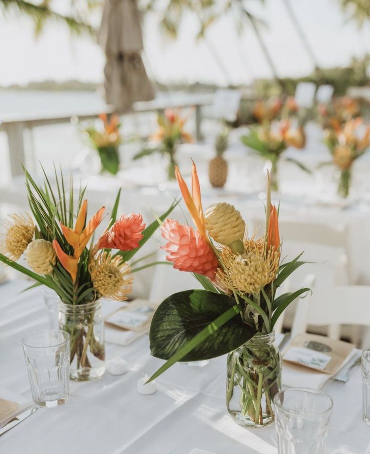 there are flowers in vases on the table at this wedding reception with white tables and chairs