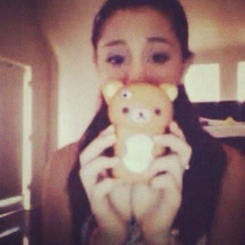 a woman is holding a teddy bear in her hands while taking a selfie with the camera