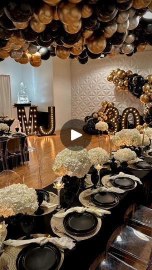 a table set with black plates and gold balloons